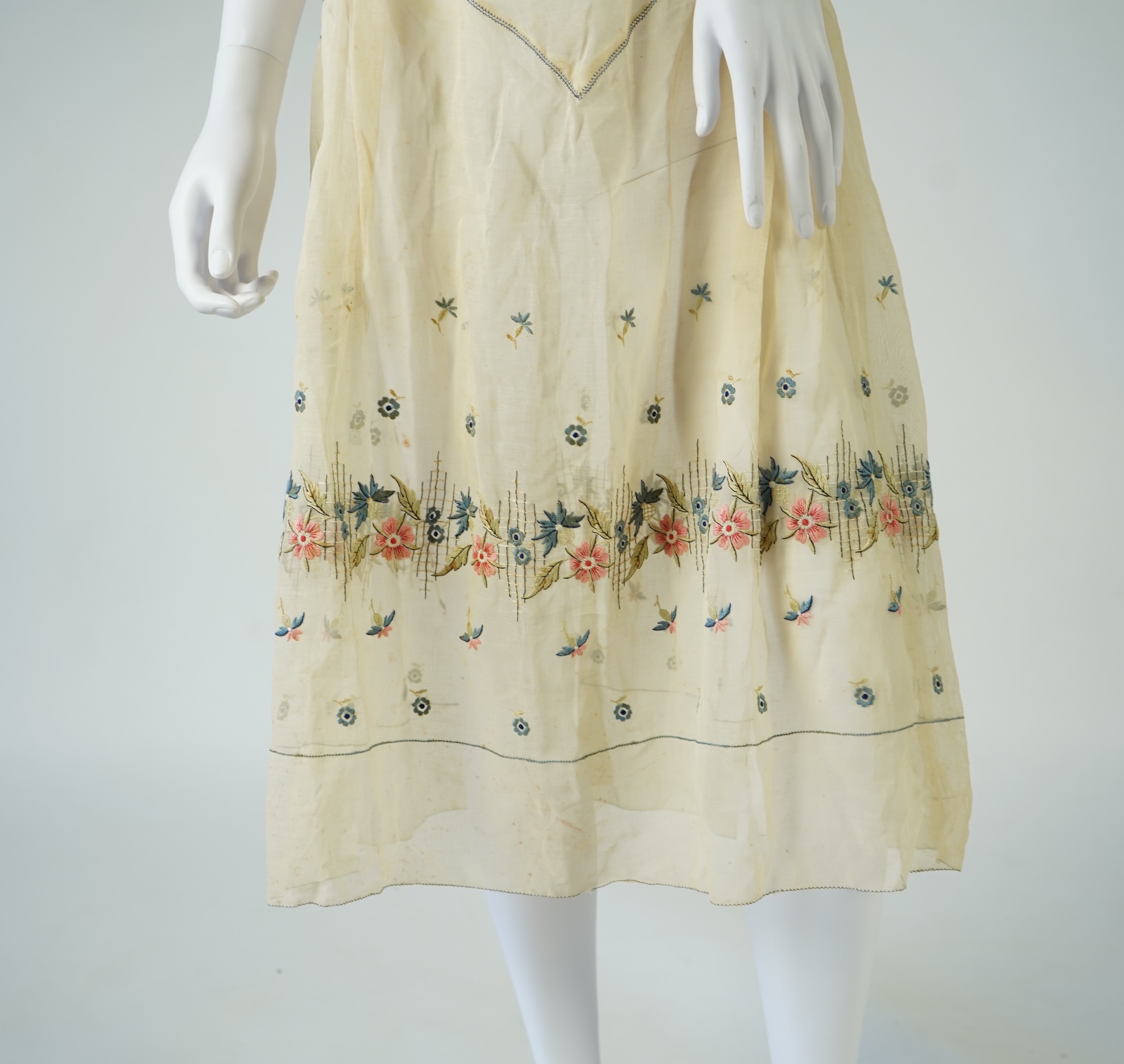 An unusual 1920's fine cream lawn summer dress with hand embroidered blue, pink, flowers, tie and picot edging., 116cm long. Condition - some small rust stains and one small tear at the back right shoulder.